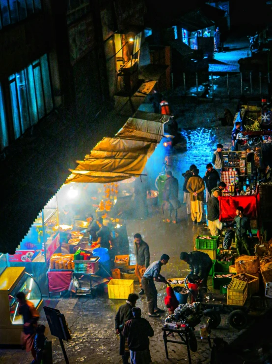 people gather in an outdoor market with brightly colored lights