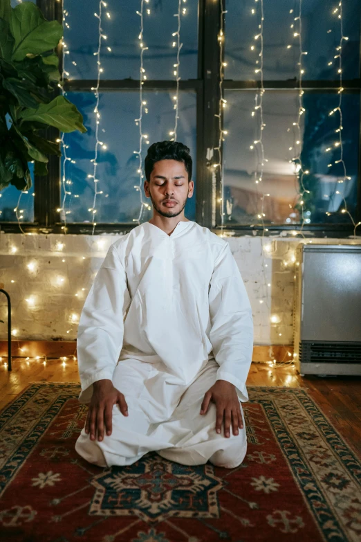 man sitting on the floor with lights on behind him