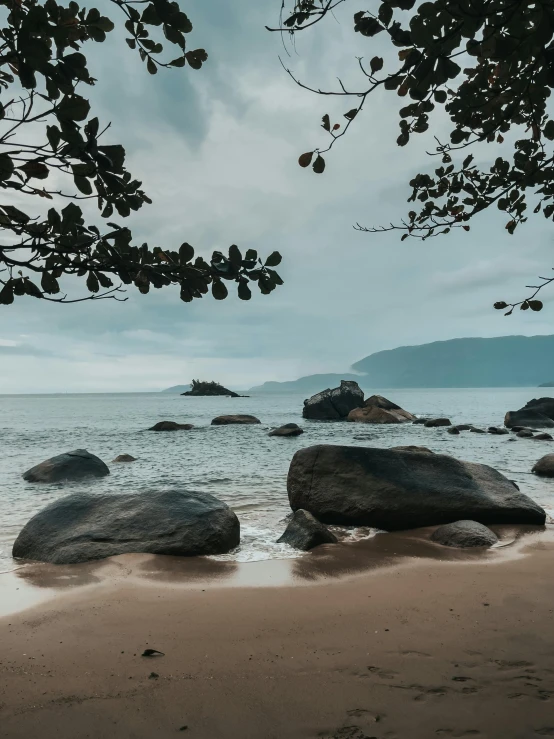 an empty beach has several rocks in the water