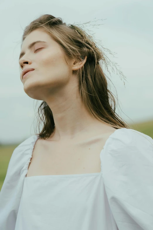 a woman with eyes closed, is wearing white clothing