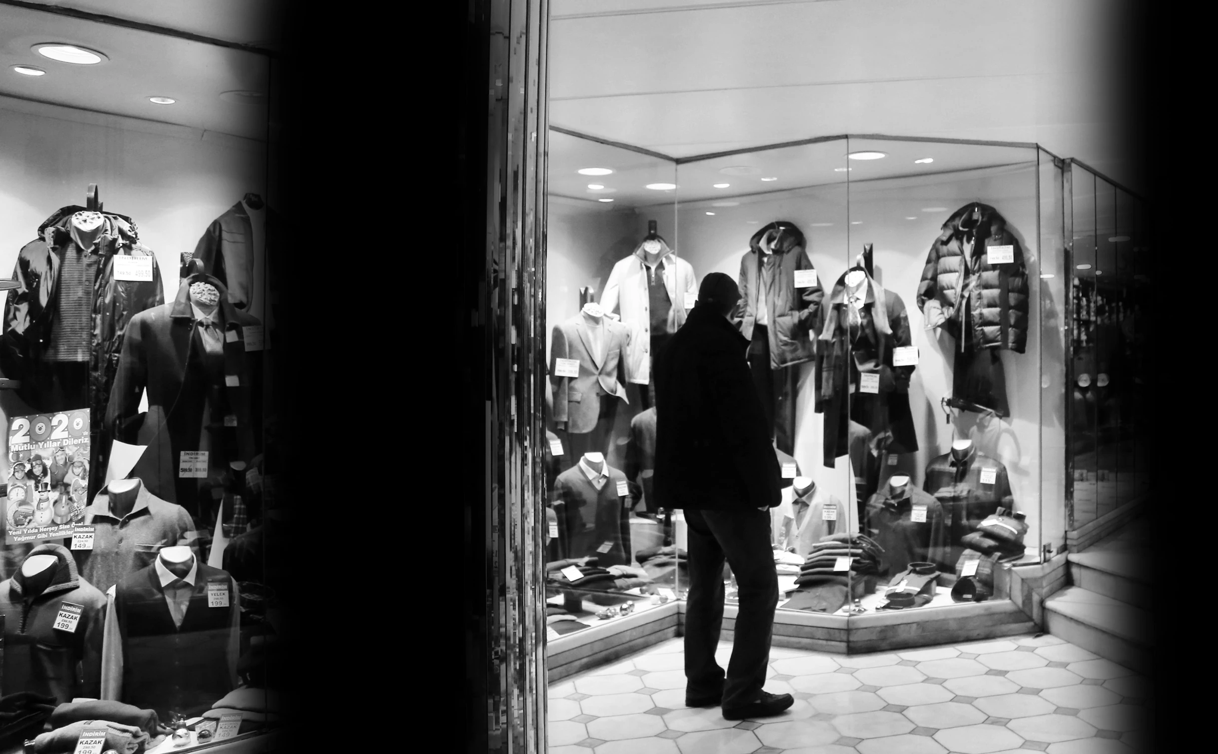 two men stand in a window that displays clothing