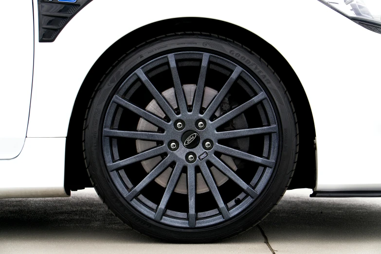 the front wheel of a white car parked on the side of the road