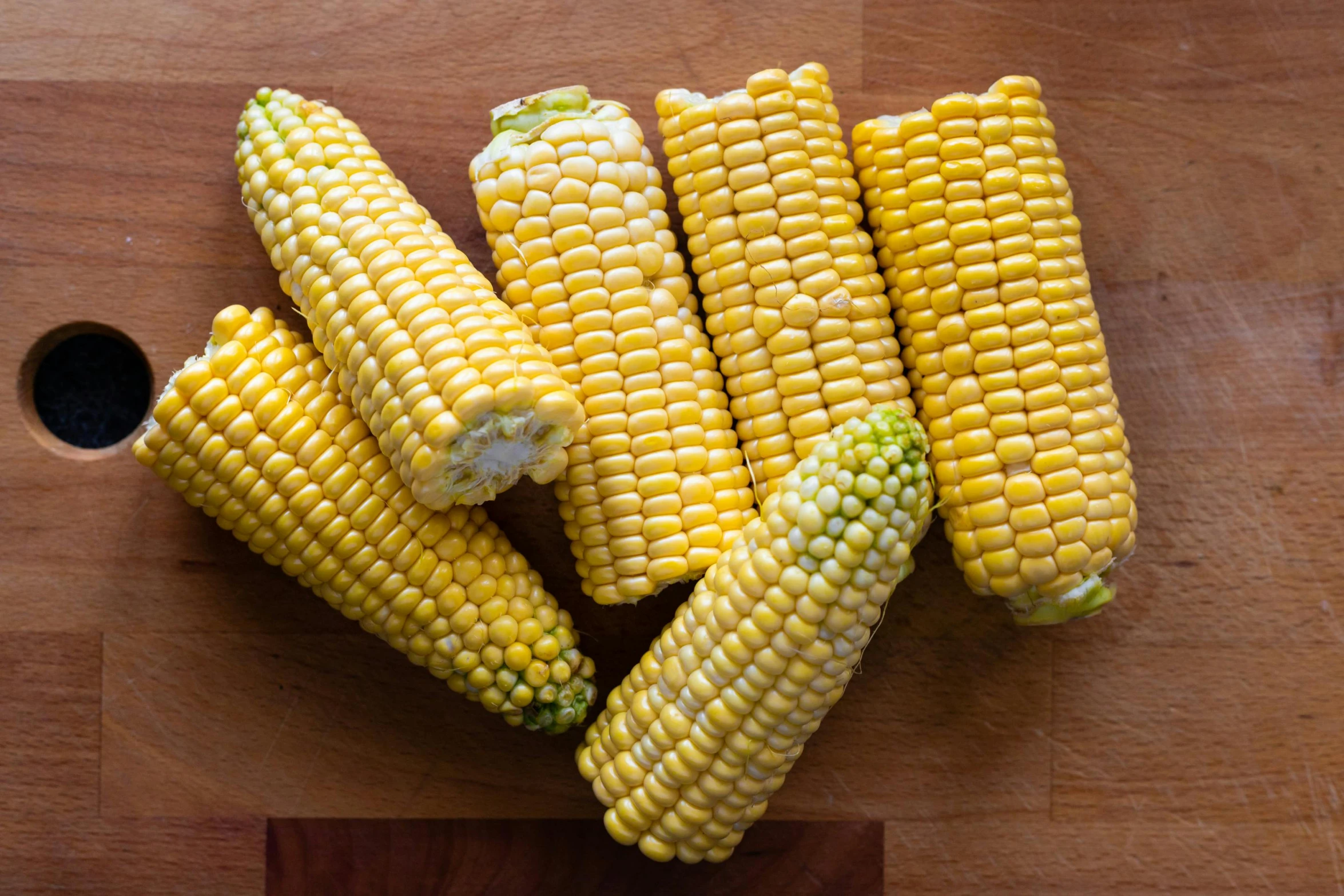 corn on the cob and bowl on a wooden surface