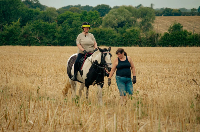 two women walking their horse in a large field