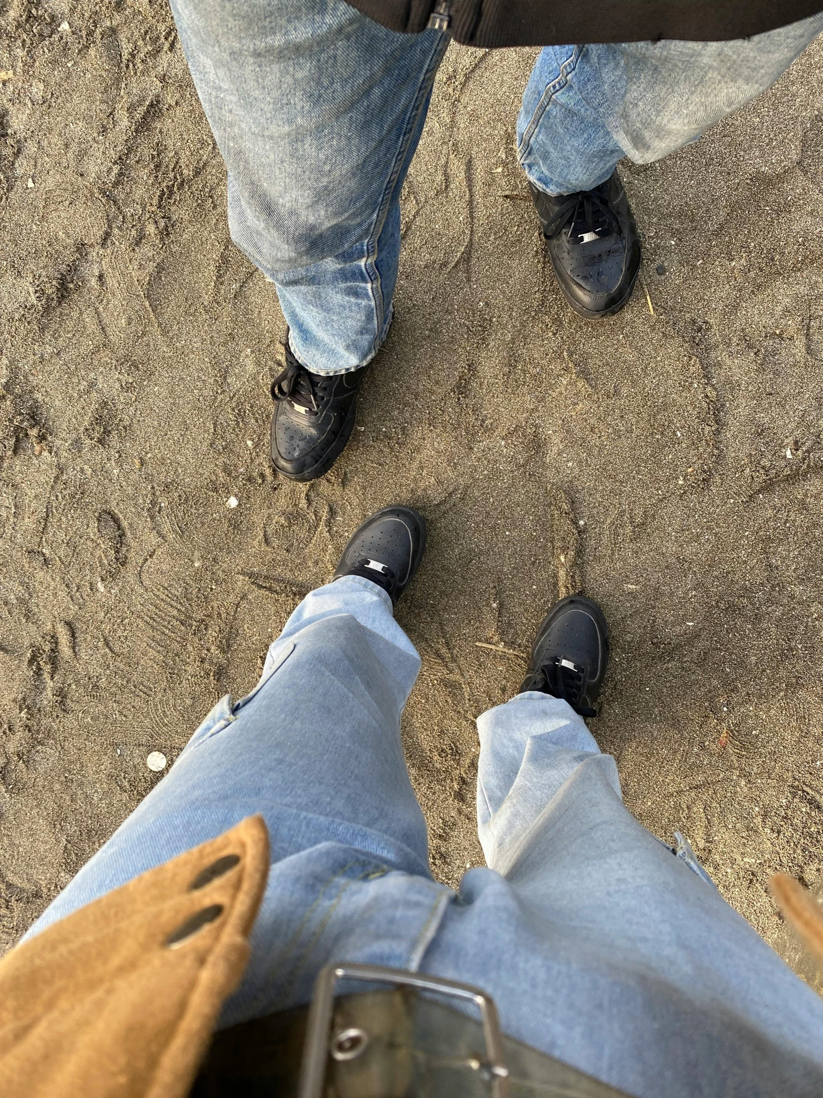 two people standing in the sand looking down at them