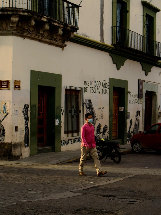 a man walking across a street past two buildings