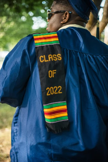 a black man wearing a blue graduation gown and hat