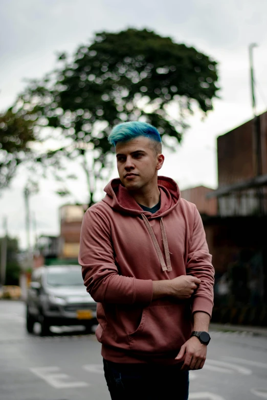 young man with blue hair and his arms crossed