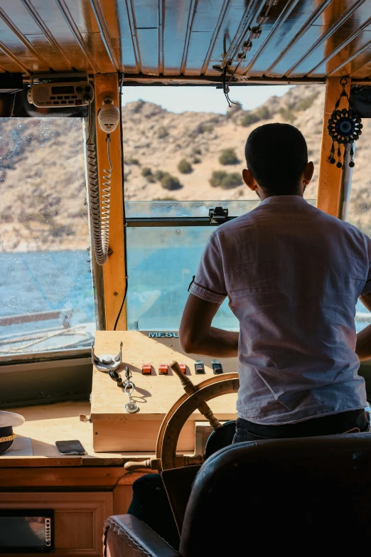 a man on a bus looking out the window at mountains