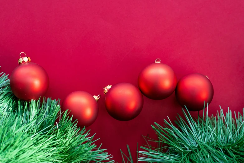 red christmas baubles hanging from green pine trees