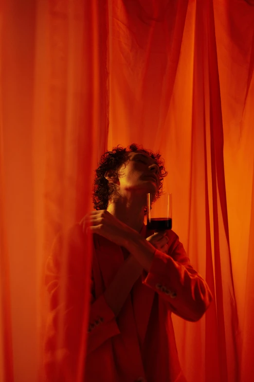 a person holding a camera and standing in front of a curtain