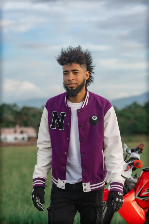 a black man with curly hair standing by his bike