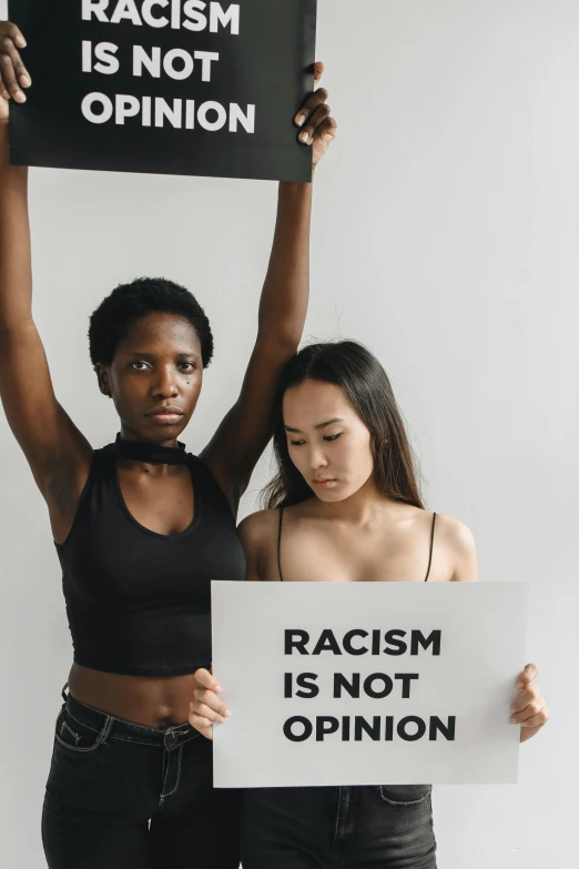 two black women holding up signs and pointing to each other