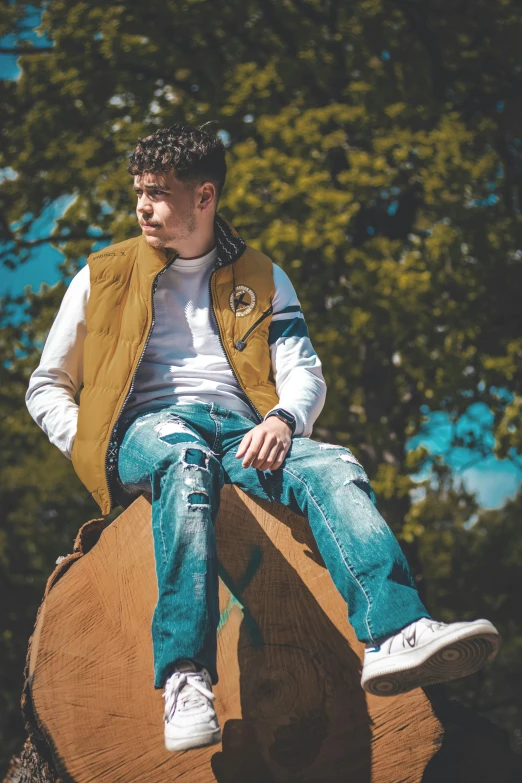 a man sitting on top of a log in front of some trees