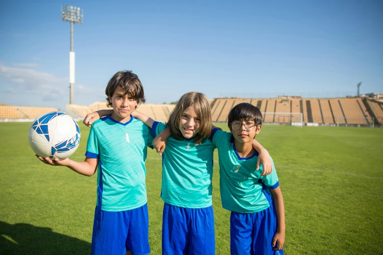 three children holding a soccer ball posing for the camera