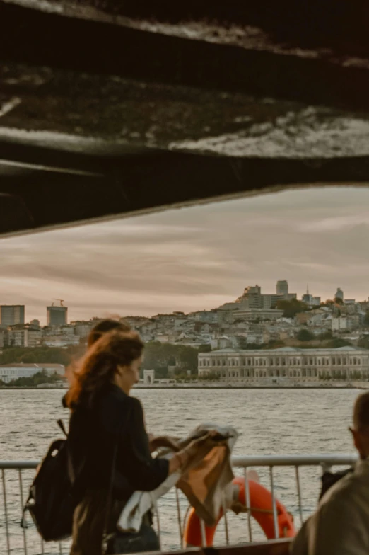 a woman looks on from a railing beside the water