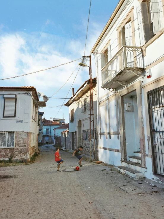 two people are walking down an old street