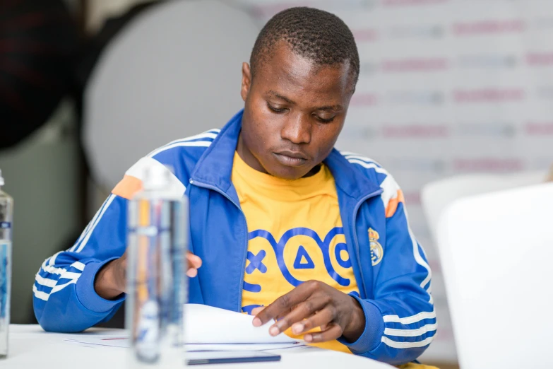 a young man in blue and yellow jacket looking at his cell phone