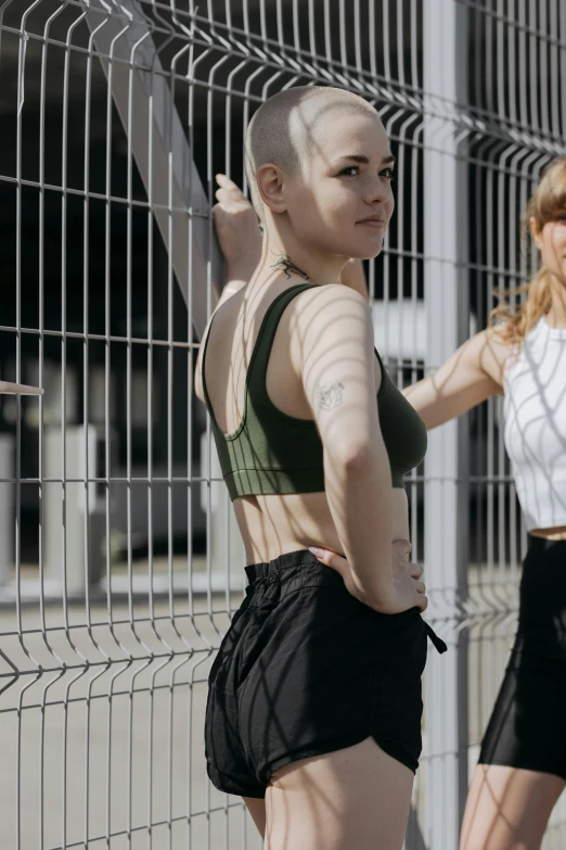 a woman with white hair wearing black shorts standing next to a fence