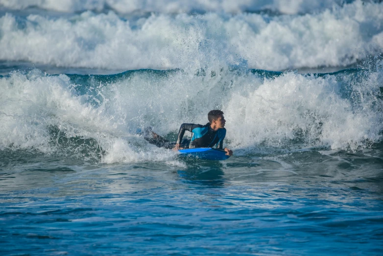 a man riding a blue surfboard on a wave in the ocean