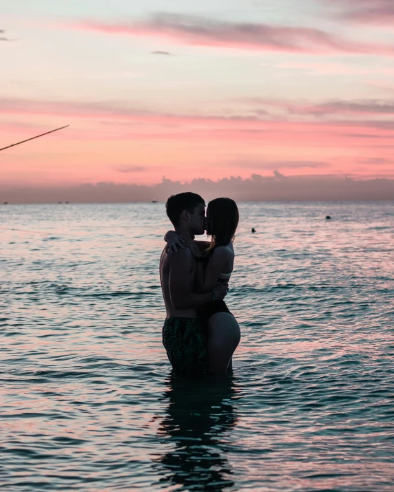 a man and woman kissing in the ocean