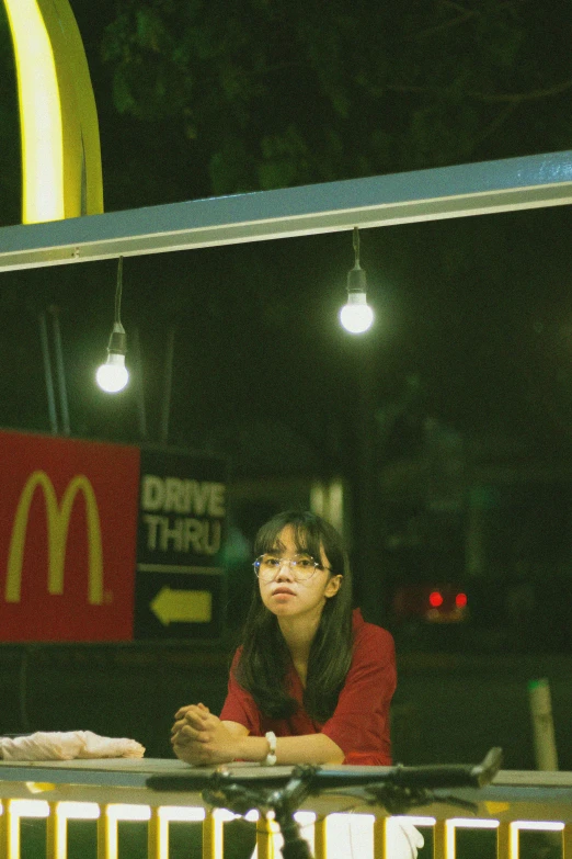 a woman sitting at a table in front of a mcdonald's sign