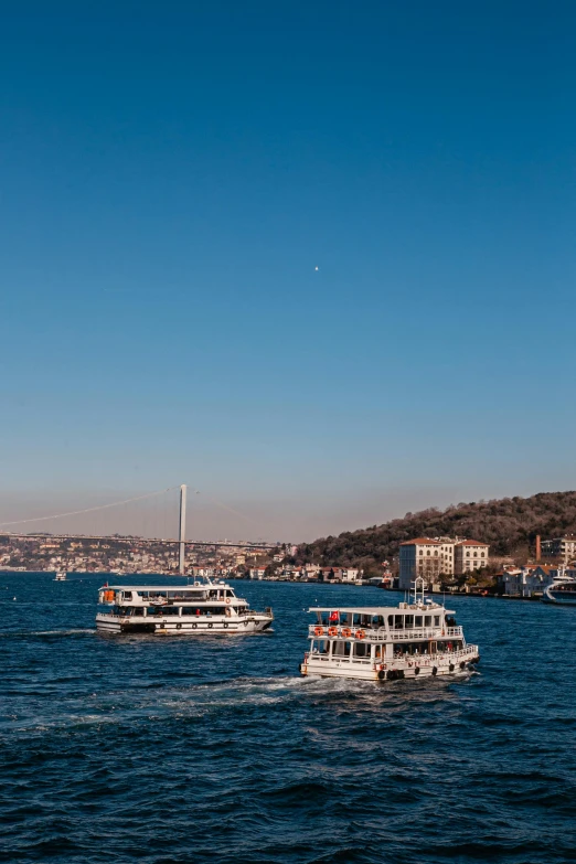 boats on a large body of water with buildings in the background