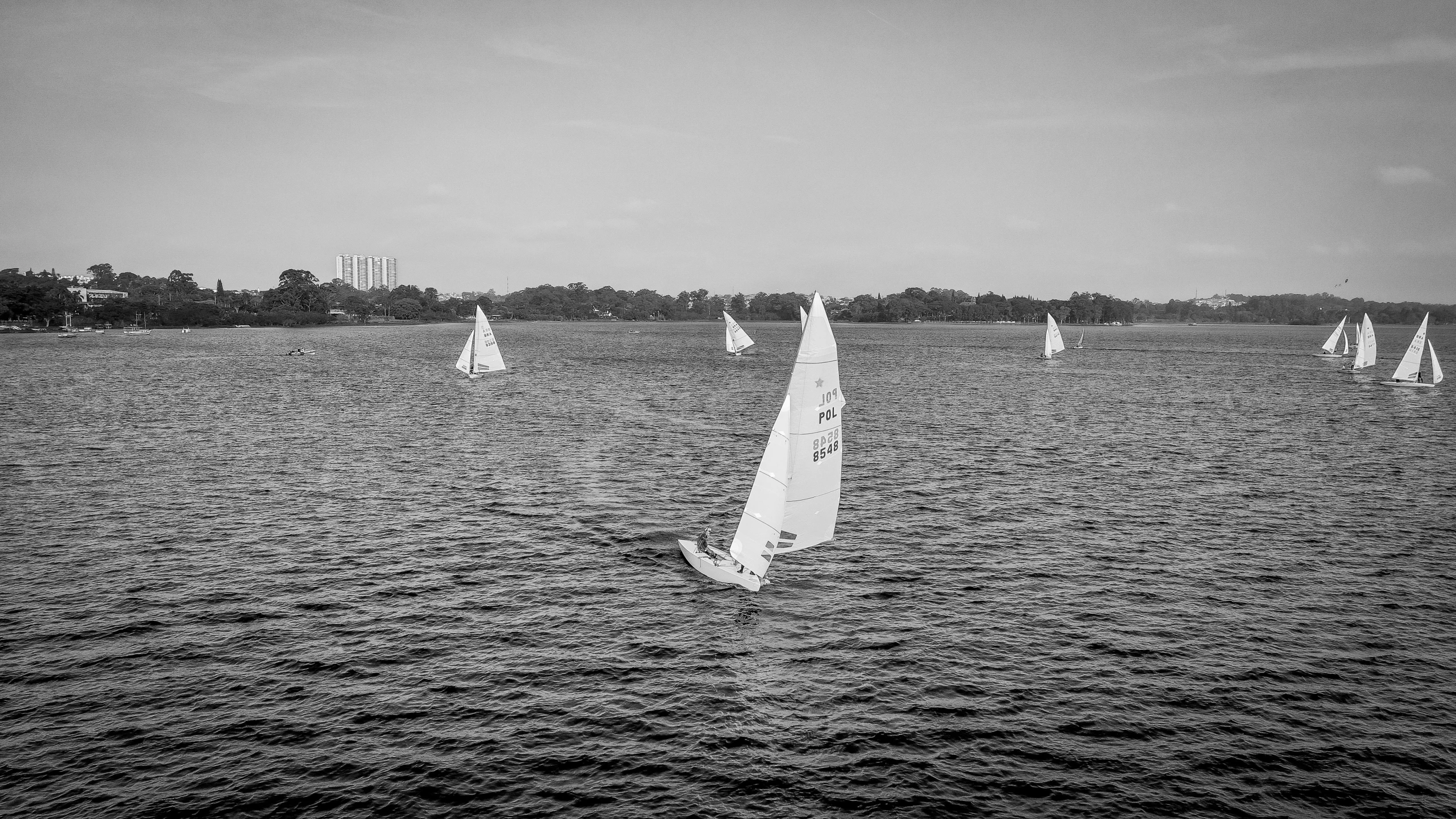 sail boats are sailing in the ocean on a cloudy day