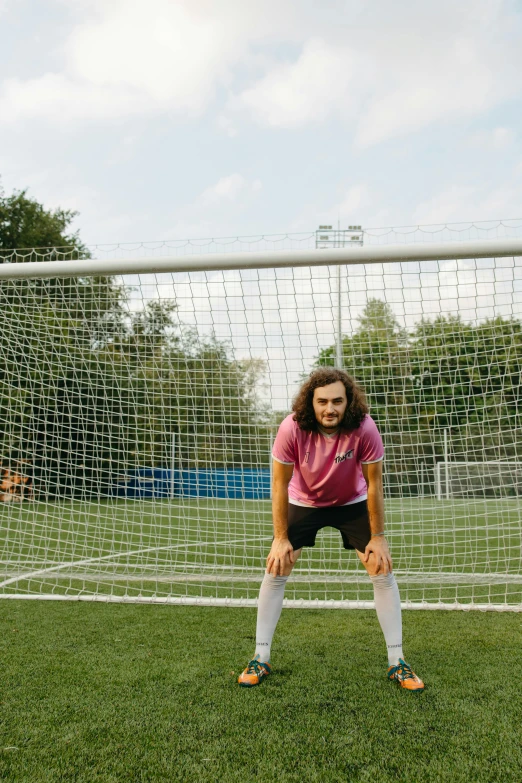 a young female is posing for the camera in front of the goal