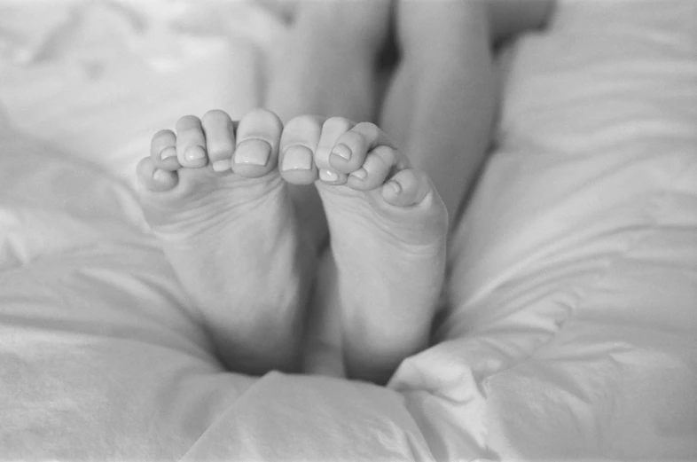 a close up of a person's feet resting on the bed