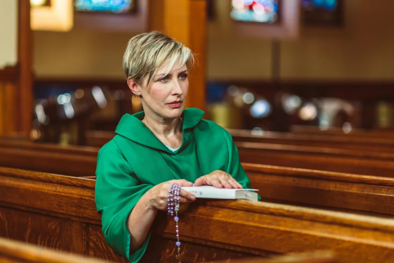 the woman stands in the pews looking into the distance