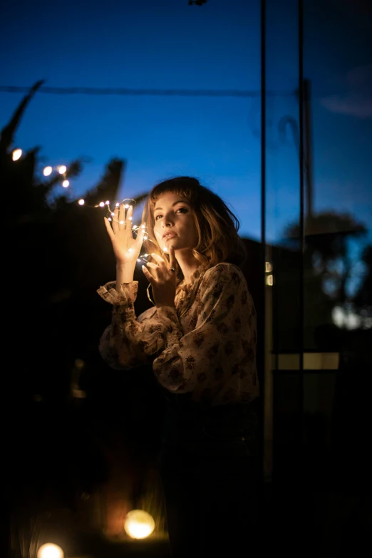 the woman is holding two lit candles and looking away