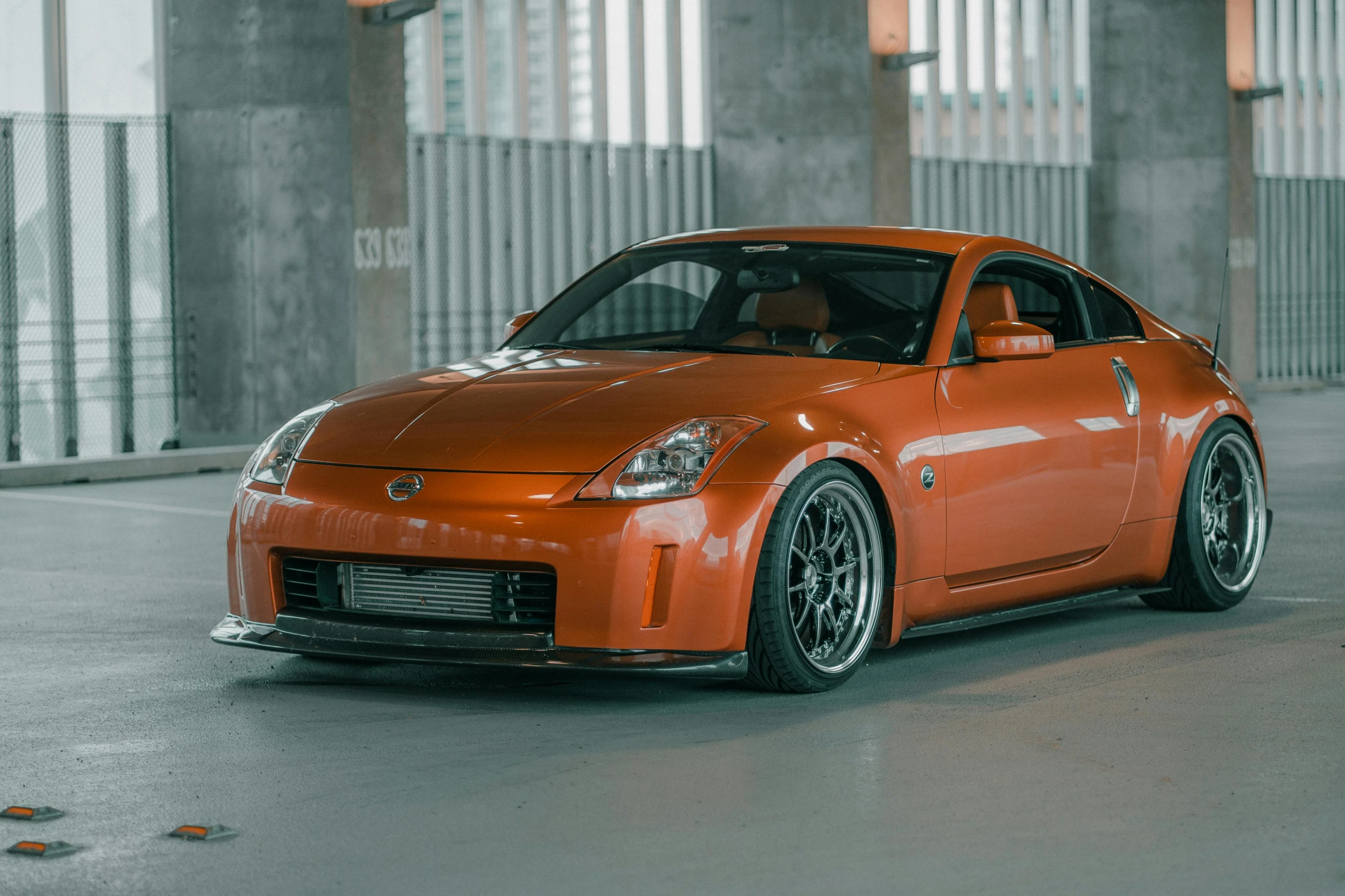 an orange sports car is parked in front of a wall