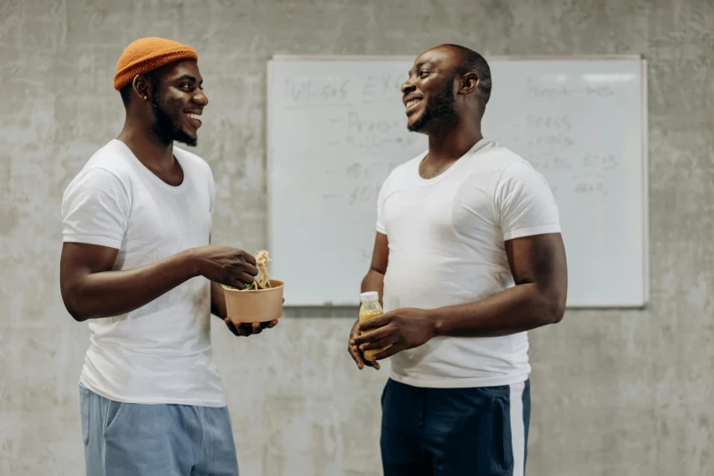 two men standing talking in front of a whiteboard