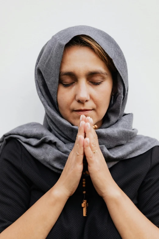 a woman wearing a black top has her hands folded as she holds her hands together