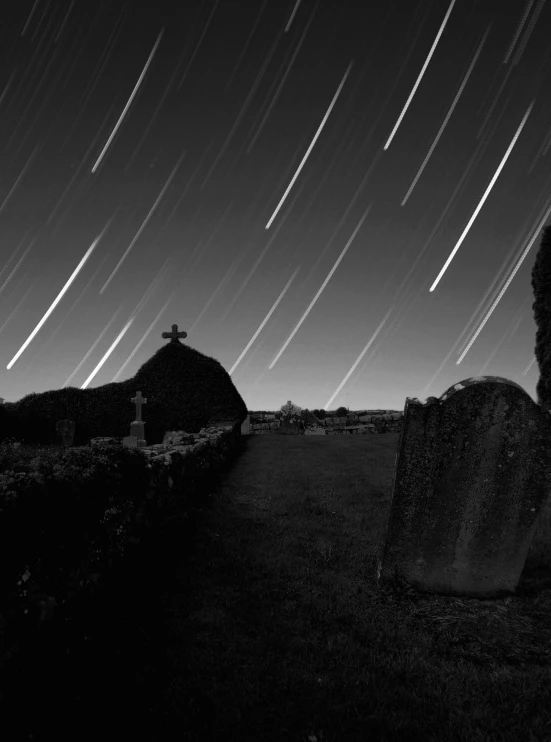 star trails above a graveyard at night