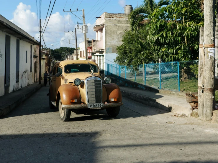 an old timey car driving down a street near houses