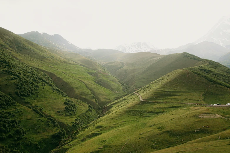 a small white building nestled in between two green hills