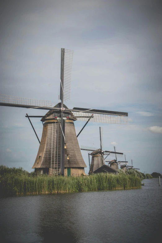 two windmills are standing on land in the water