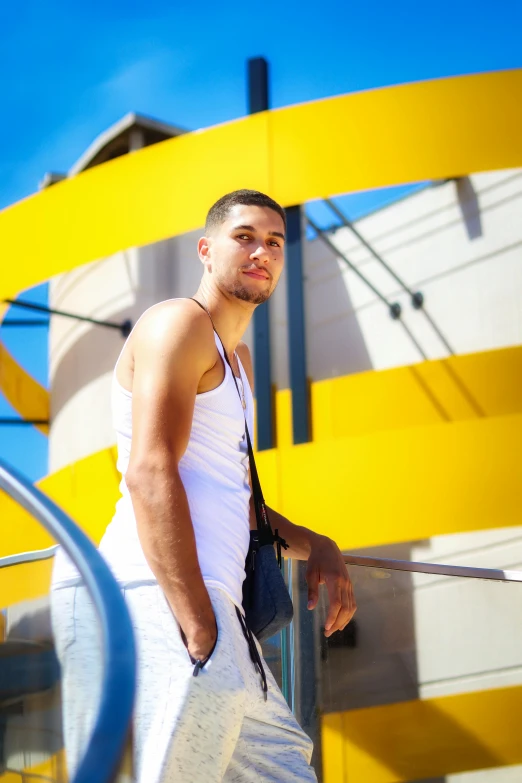 man in tank top standing against a metal hand rail