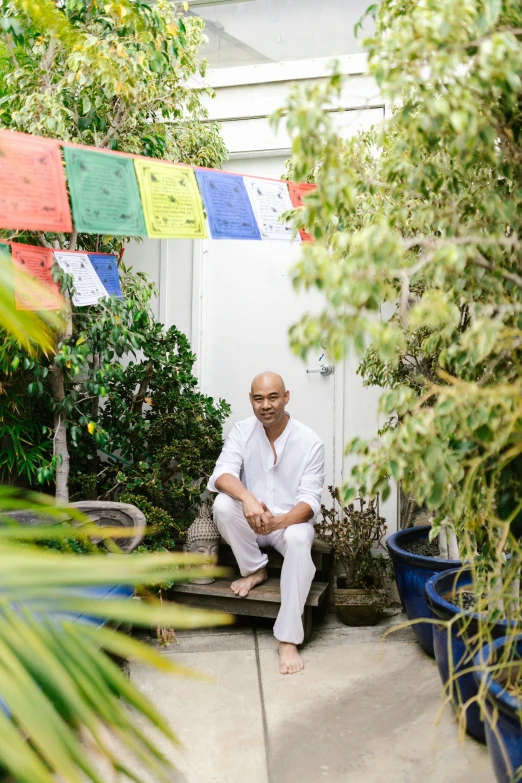 a man in white shirt sitting in a room with plants