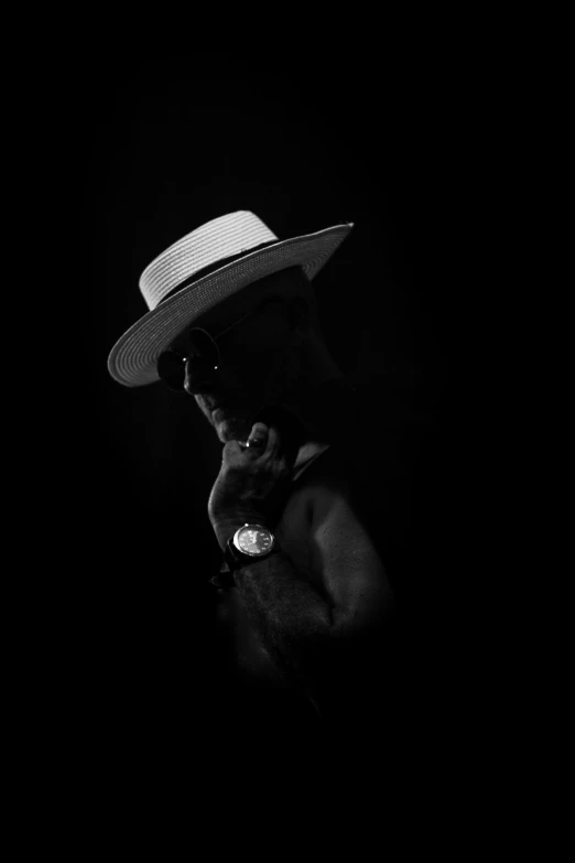 black and white pograph of a man in hat smoking cigar