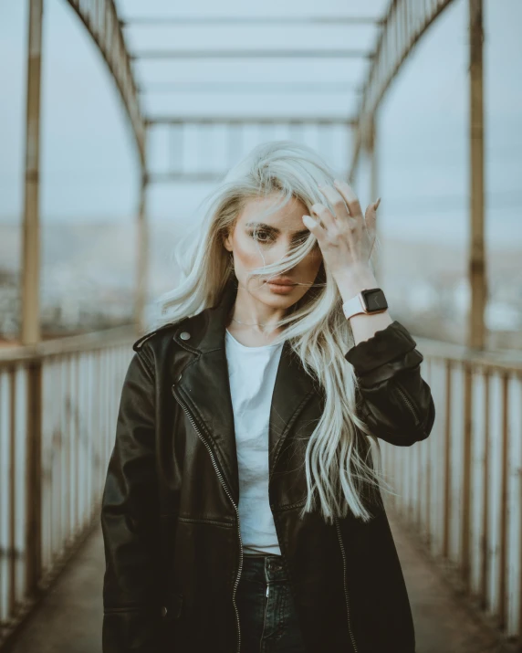 woman with blond hair wearing black jacket posing for camera