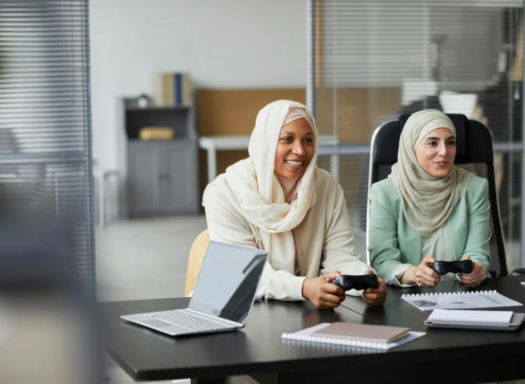 two woman sitting in chairs smiling and holding video game controllers