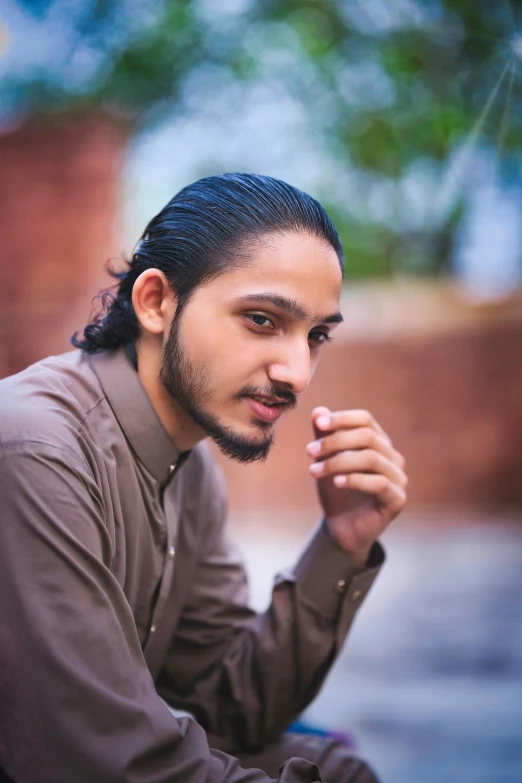 a man with long black hair sitting down