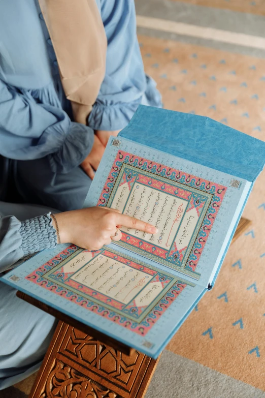 the back of a person with their hand on top of a cross stitch book