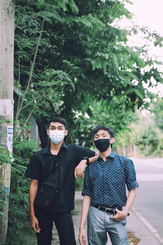 two people wearing masks standing next to a tree