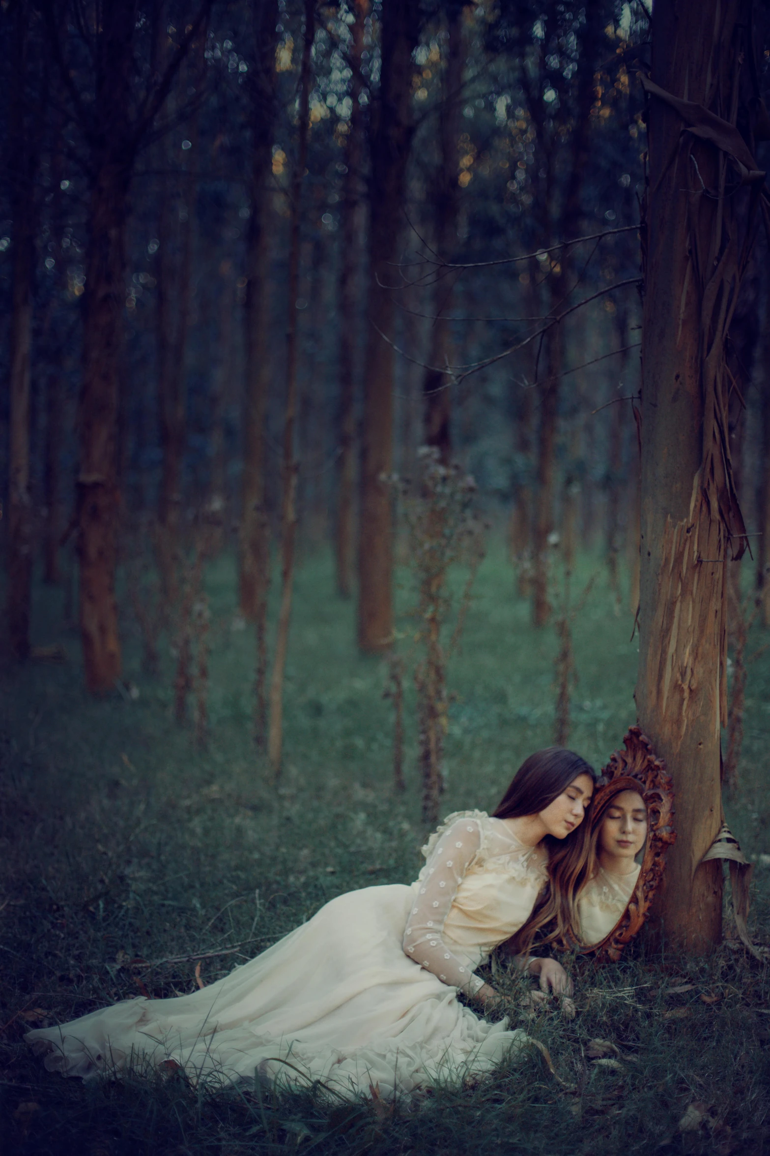 two women dressed in white dress sitting in the woods