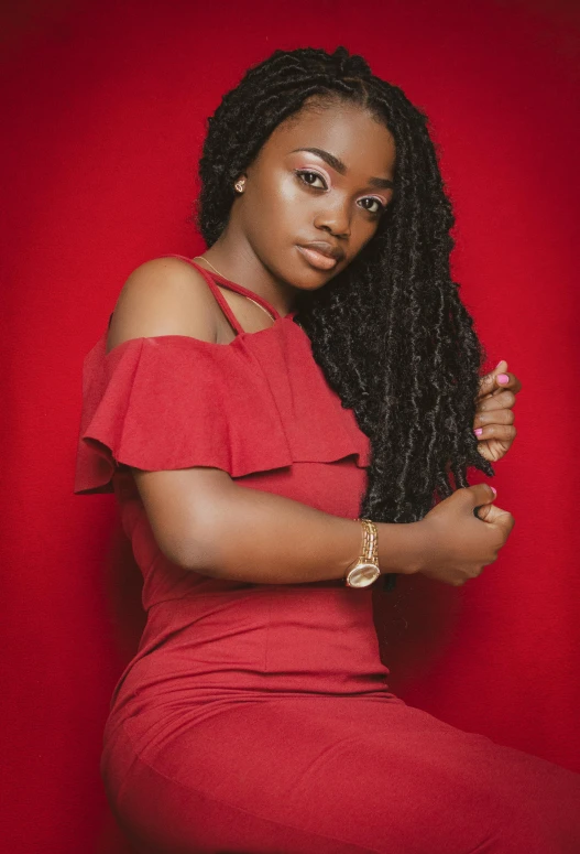 a black woman sitting on a red chair wearing a red dress