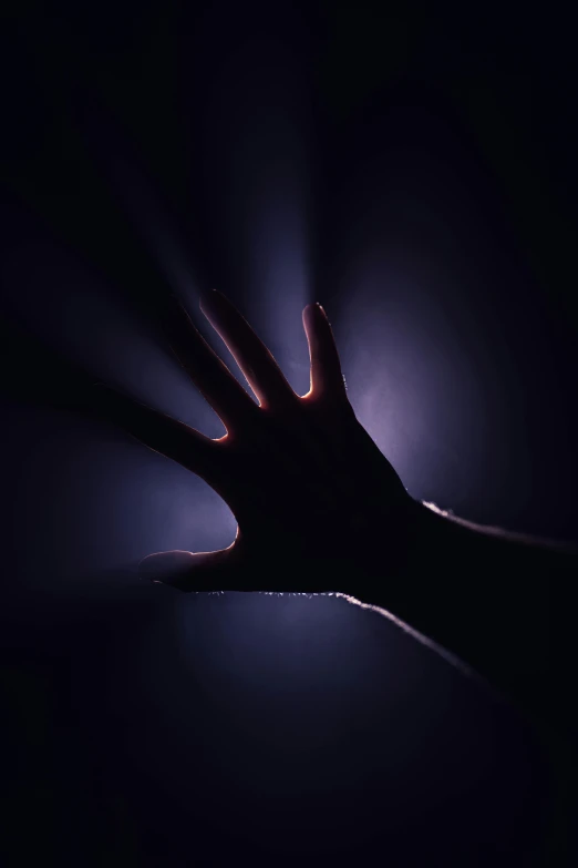 silhouette of hands touching one another with a bright light in the background